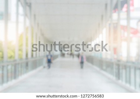 blur background image of empty modern sky walk way in city with people and sunlight abstract gray blur bokeh.