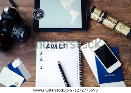 notepad, credit cards, passport, ticket, camera, phone and compass on a wooden background