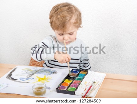 Cute little boy of two years having fun painting at home