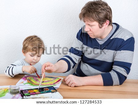 Father and little boy of two years having fun painting at home
