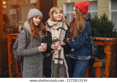 three pretty girls standing in a spring city with coffee