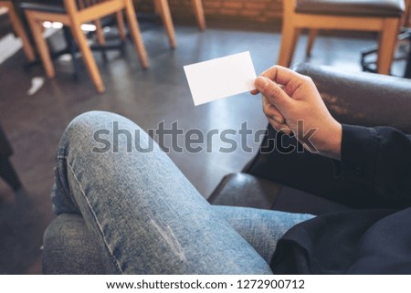 A woman holding a white empty business card while sitting in office
