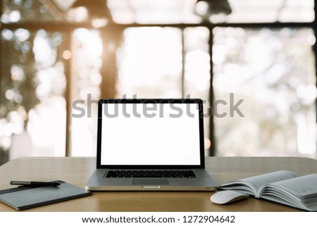 Workspace wooden desk with Mockup Laptop with blank screen and wireless mouse and graphics tablet and notebook in home blurred background of bokeh.