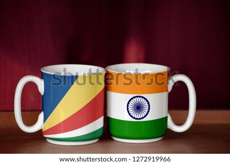 India and Seychelles flag on two cups with blurry background