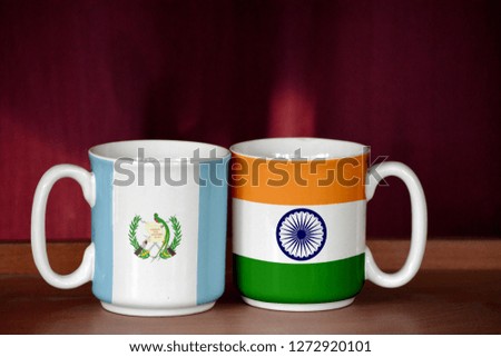 India and Guatemala flag on two cups with blurry background