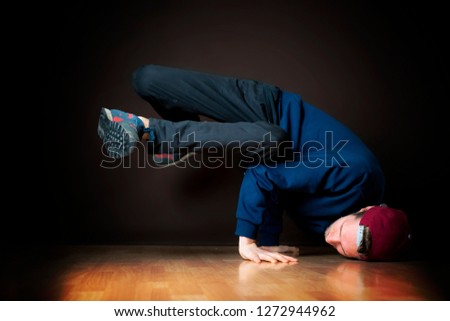 closeup photo of male break dancer performing stance against dark background