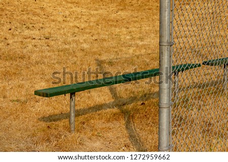 green bench on edge of summer ball field 