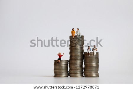A concept of income disparity by social class. Miniature people with a pile of coins.  Royalty-Free Stock Photo #1272978871