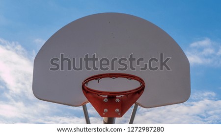 Upwards view of basketball hoop against a bright blue sky