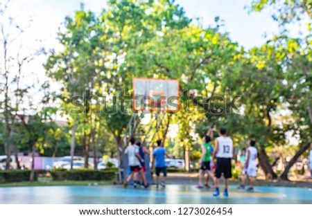 Blurry image of elderly men and teens playing basketball in the morning at BangYai Park , Nonthaburi in Thailand.