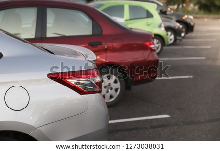 Closeup of rear or back side of bronze car with  other cars parking in parking area in the evening of sunny day. The mean of simply transportation in modern world.