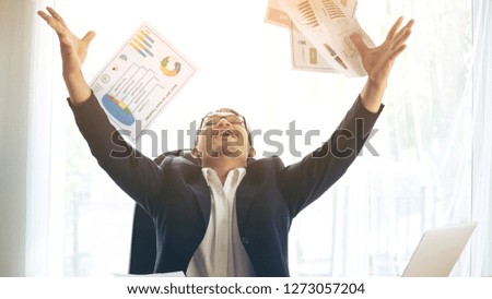 business man celebrating happy winner throwing papers on office desk business district , business success concept