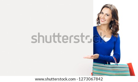 Happy smiling woman with shopping bags, showing blank signboard or copy space for some slogan or text, isolated against white background