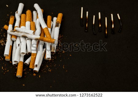 A pile of cigarettes and burnt matches on a black background. The concept of choosing a healthy lifestyle. World No Tobacco Day. Stop smoking. Fighting cigarettes