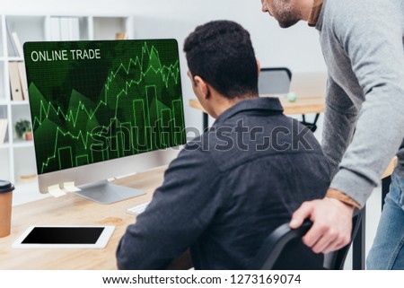 cropped shot of business colleagues using desktop computer with online trade graphs on screen in office