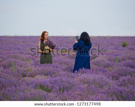 Two girls take pictures of each other in a lavender field.