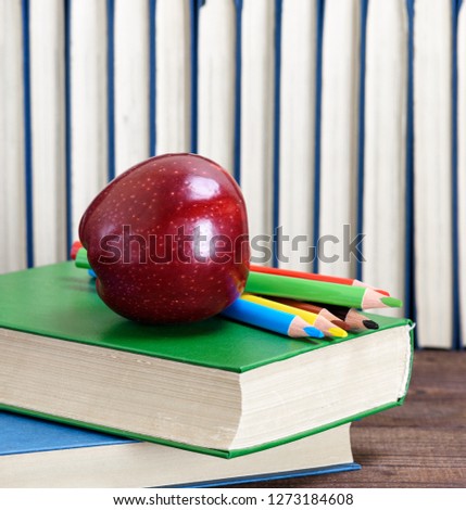 ripe red apple lying on a stack of books, abstract background back to school
