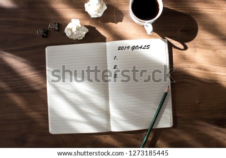 2019 goals list with notebook , cup of coffee over on wooden background.