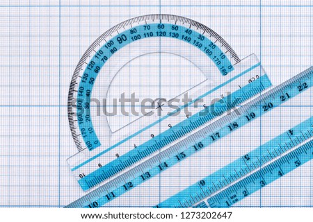Backgrounds and textures: group of transparent plastic rulers, arranged on graph paper, educational abstract