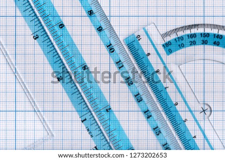 Backgrounds and textures: group of transparent plastic rulers, arranged on graph paper, educational abstract