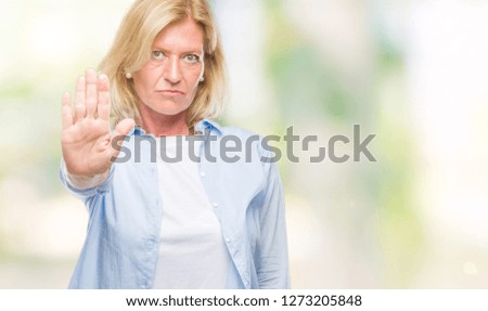 Middle age blonde woman over isolated background doing stop sing with palm of the hand. Warning expression with negative and serious gesture on the face.