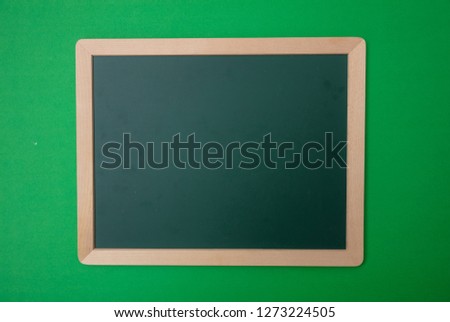 Green blank empty chalk board with wooden frame, green wall background. Space for text