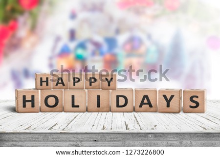 Happy Holidays sign made of wooden toy cubes with a winter landscape in the background