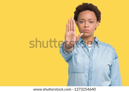 Young beautiful african american woman over isolated background doing stop sing with palm of the hand. Warning expression with negative and serious gesture on the face.