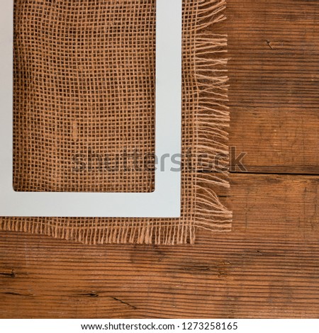White empty frame on the old rustic wooden brown background and natural canvas and with copyspace for picture, text, blog