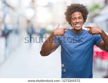 Afro american man over isolated background smiling confident showing and pointing with fingers teeth and mouth. Health concept.
