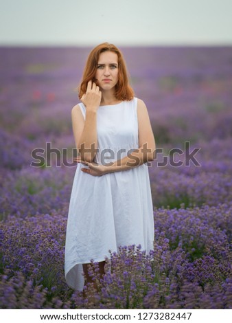 Young girl in white dress, posing in a lavender field.