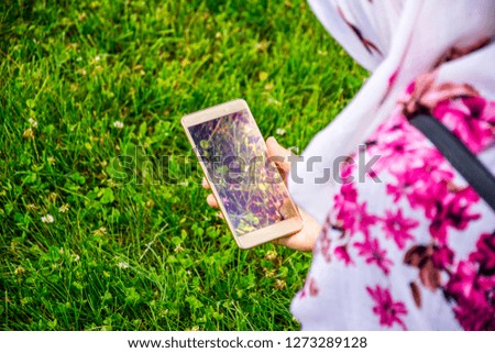 The muslim girl holding mobile phone in her hands while sitting 