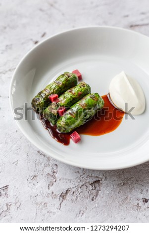 Stuffed grape leaves with meat and rice served with yogurt on a plate called dolmadakia or dolma. Traditional turkish and greek cuisine.