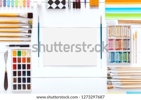 Creative learning concept, different supplies colorful accessories set for art work on white wooden background, paintbrushes paintbox crayons pencil paper on table, back to school. Top view, flat lay