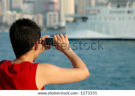 Lady in red shirt taking a picture of a cruise ship with a digital camera