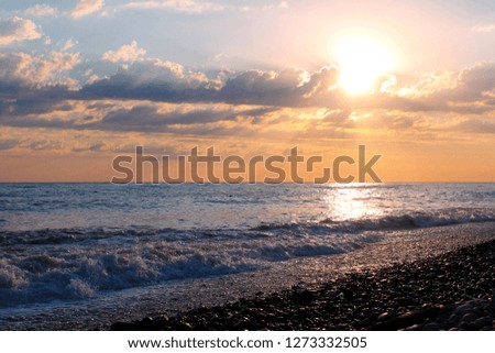 Sunset over the sea, seashore, pebbles and waves