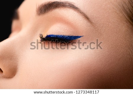 cropped view of closed female eye with blue eyeliner and perfect skin Royalty-Free Stock Photo #1273348117