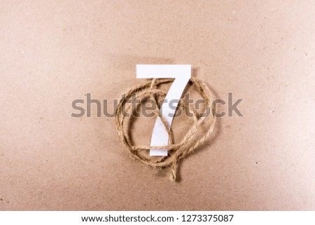 7 number seven, graphic white digit and creative typography with rope on ecological, paper background