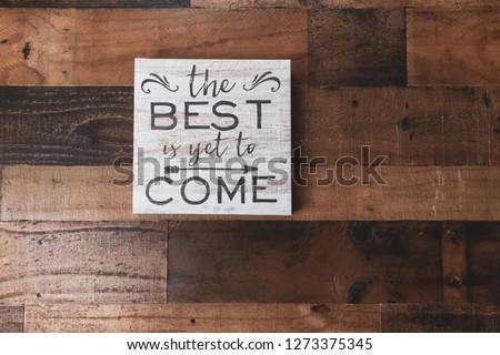 Inspirational quote  "The best is yet to come" on rustic woodgrain background