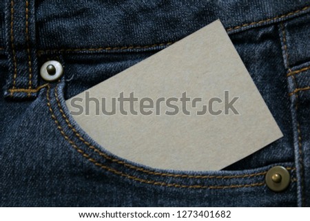 blank white paper or card in front pocket of blue jeans with copyspace for sale text or business concept