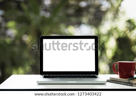 Workspace wooden desk with Mockup Laptop blank screen and coffee cup,at nature blurred background of bokeh.
