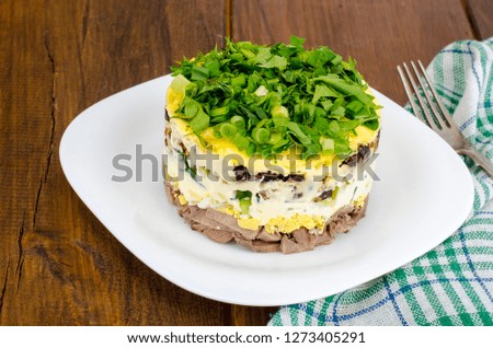Layered portion salad with meat, cucumber, egg and mayonnaise. Studio Photo
