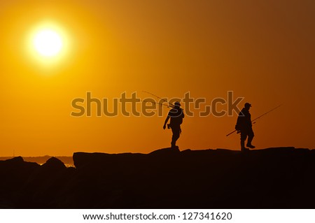 Two men walking with rods at sunset
