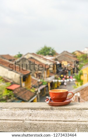 Vertical photo of cup of hot Cappuccino with the Hoi An ancient town background