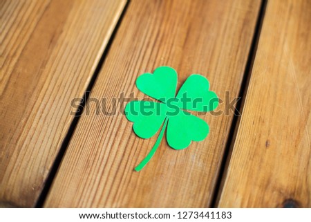 fortune, luck and st patricks day concept - green paper four-leaf clover on wooden background
