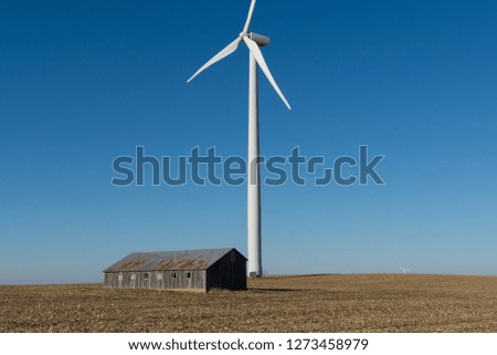 Old wooden barn and windmill in open farmland.