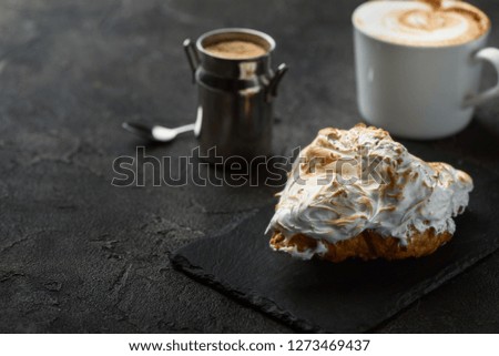 croissant with meringue and coffee on a dark background, breakfast
