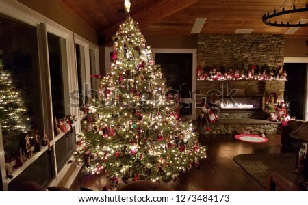 Stunning Christmas Tree in  Rustic Lodge at Night with Large Stone Fireplace Glowing in the Background; Happy Places, Cozy Vacation Ideas, Family Royalty-Free Stock Photo #1273484173