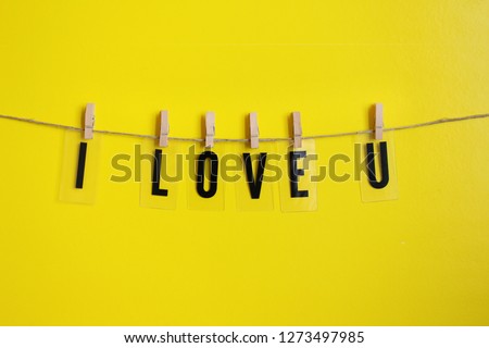 This is a picture of the letters hanging on a thin thread in honor of Valentine's Day on a yellow background
