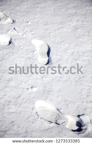 footsteps leaving boot prints on a snowy ground in winter